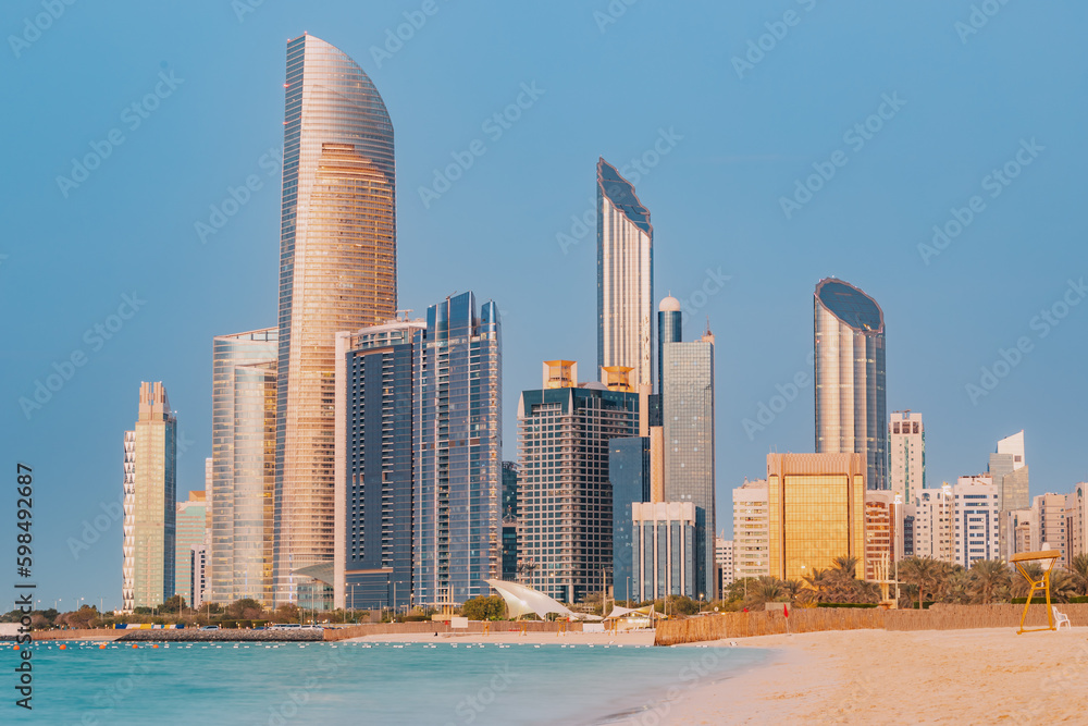 Stunning sandy beach near Corniche seaside embankment with great sunset view of Abu Dhabi, UAE towering skyscrapers Stunning sandy beach near Corniche seaside embankment with great sunset view of Abu Dhabi, UAE towering skyscrapers