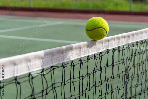 Close up of tennis ball clips the top of the net. tennis ball hit the net and goes to the other side. © fery