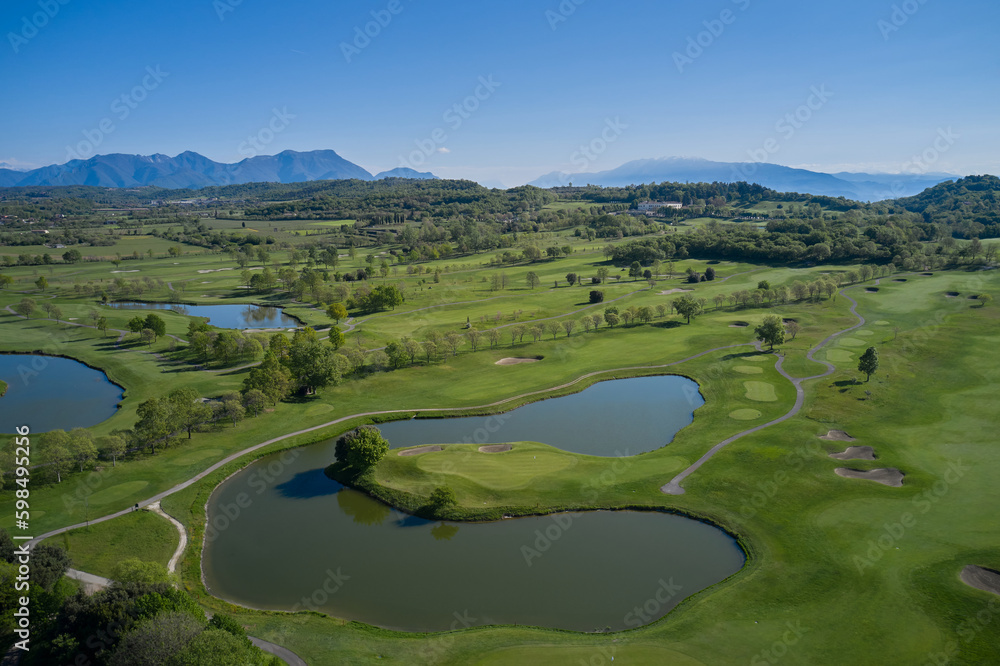 Great view, outlook, panorama at the beautiful golf course with the mountains at the back. Beautiful panorama of golf course and Alps. Golf Course in front of a beautiful landscape scenery.