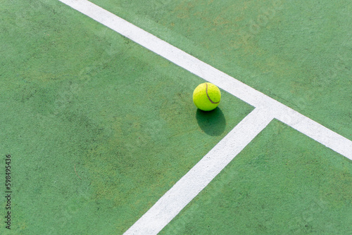 Yellow tennis ball on green court and white lines. Top angle view of tennis ball on court. © fery