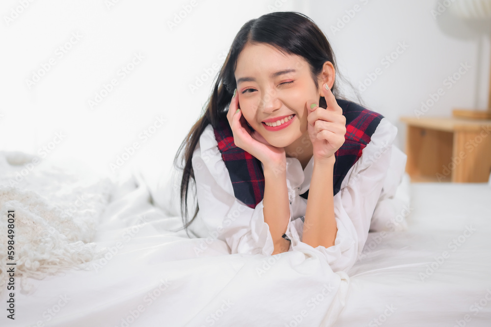Beautiful asian woman lying on bed while pointing finger to the camera with joyful expression. Beautiful asian woman lying on bed while pointing finger to the camera with joyful expression.