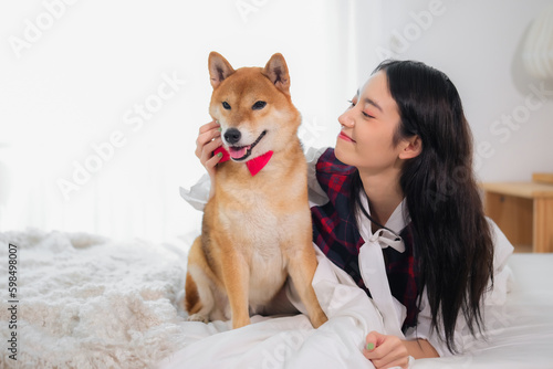 Beautiful asian woman giggled as she playfully teased her Shiba Inu dog.