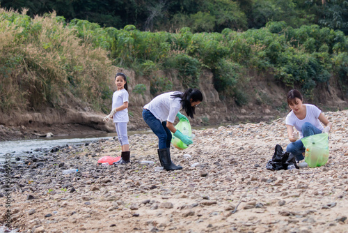 Environment and pollution caring management concept, group of Asian friends collect dirty plastic bottles in the stream for recycling, volunteer kids family pick up garbage and wastrel from tourist