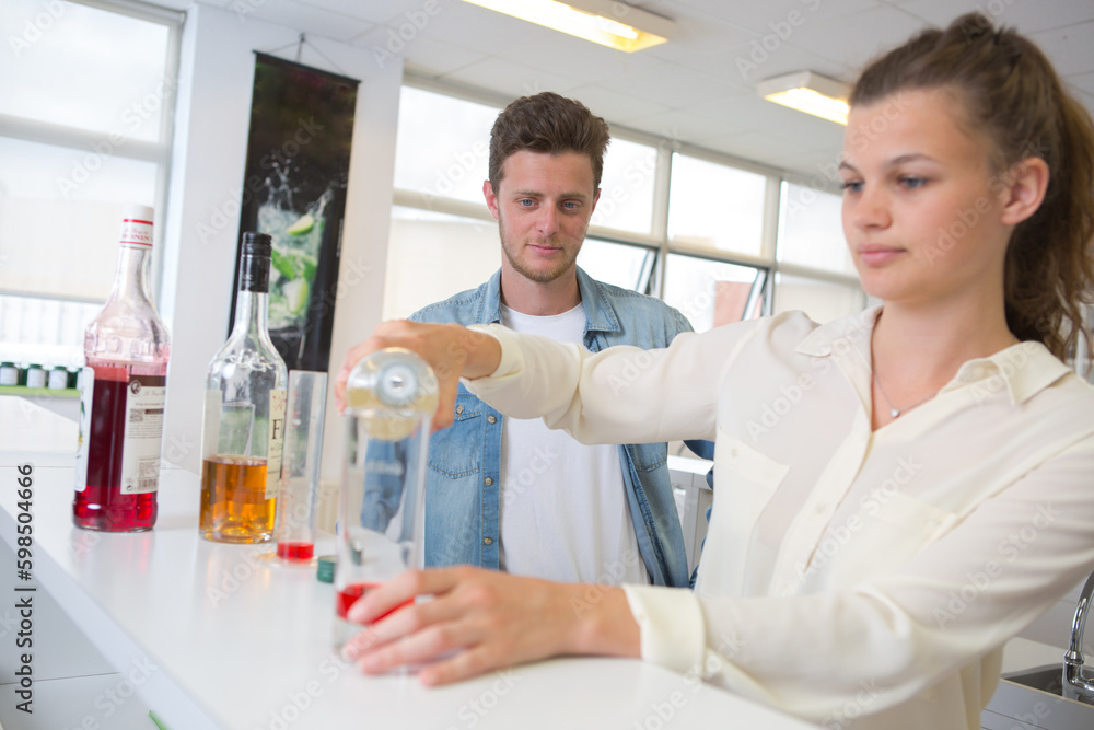 two young smiling chemists carrying out an experiment two young smiling chemists carrying out an experiment