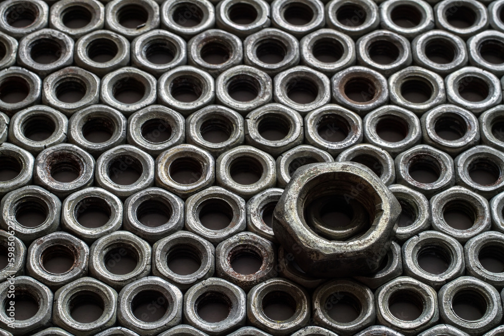 Iron nuts. One big nut against a background of small nuts. Steel fasteners.