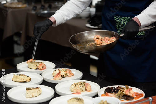 chef in the restaurant prepares saganaki, traditional Greek cheese snack that is fried in a pan or grilled