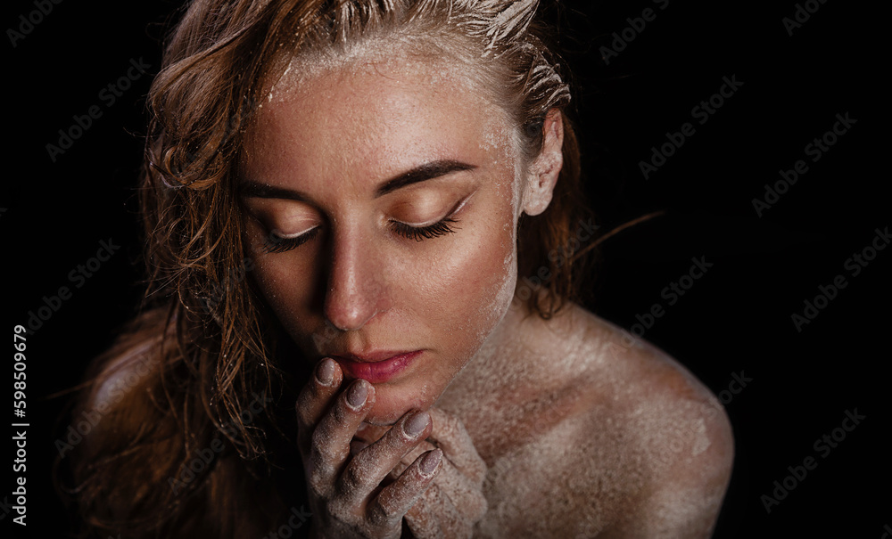 Fine art portrait. The woman's naked wet body is covered with a thin layer of flour. Creative body makeup with cracks and mud. Woman bodyart texture