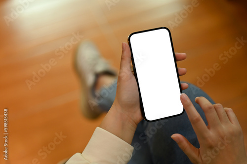 Close-up image of a woman using her smartphone while sitting in her living room.