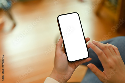 Close-up image of a woman using her smartphone while sitting in her living room.