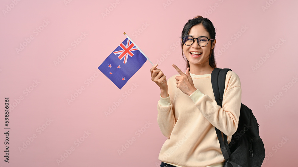 Confident pretty girl showing a New Zealand flag on pink isolated background, education concept Confident pretty girl showing a New Zealand flag on pink isolated background, education concept