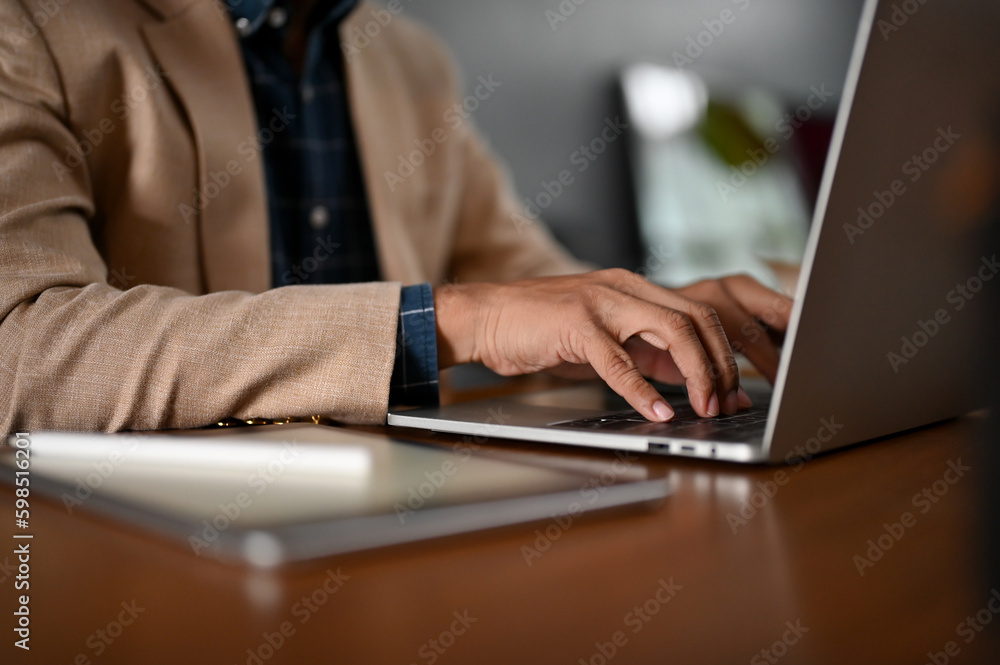 A professional businessman typing on keyboard, using his laptop computer at his desk. A professional businessman typing on keyboard, using his laptop computer at his desk.