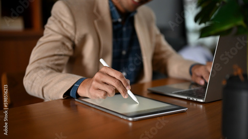 Close-up image of a professional adult Asian businessman using his laptop and tablet