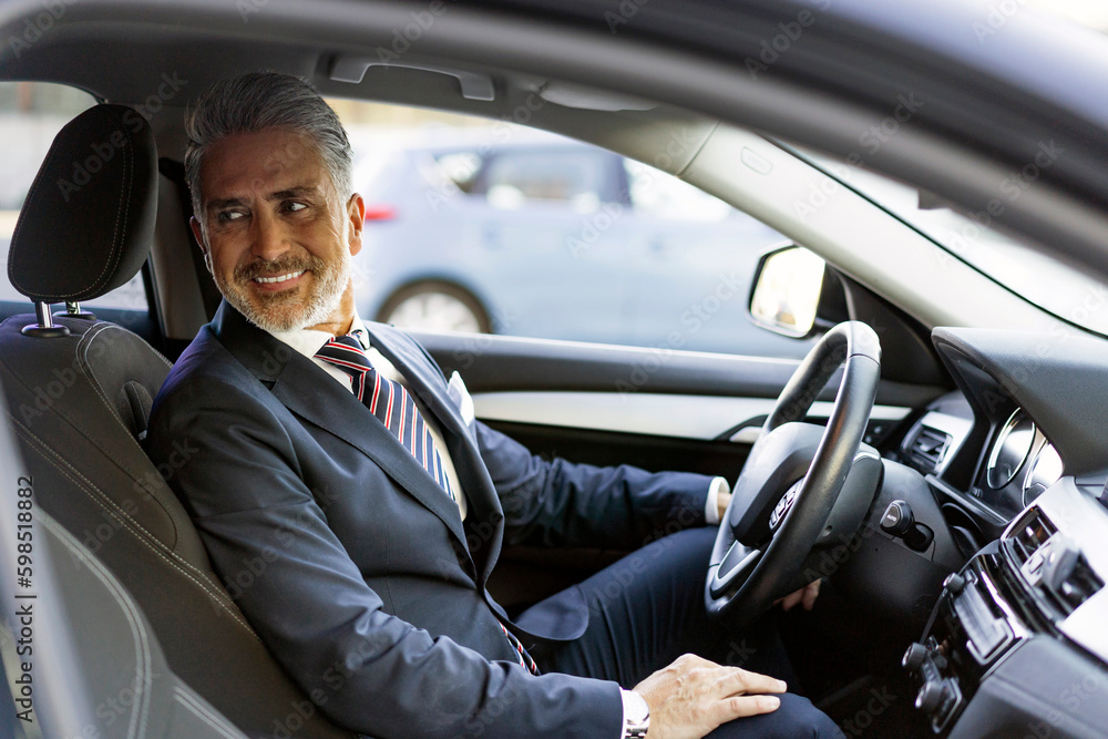 Smiling businessman sitting on driver's seat in car Smiling businessman sitting on driver's seat in car