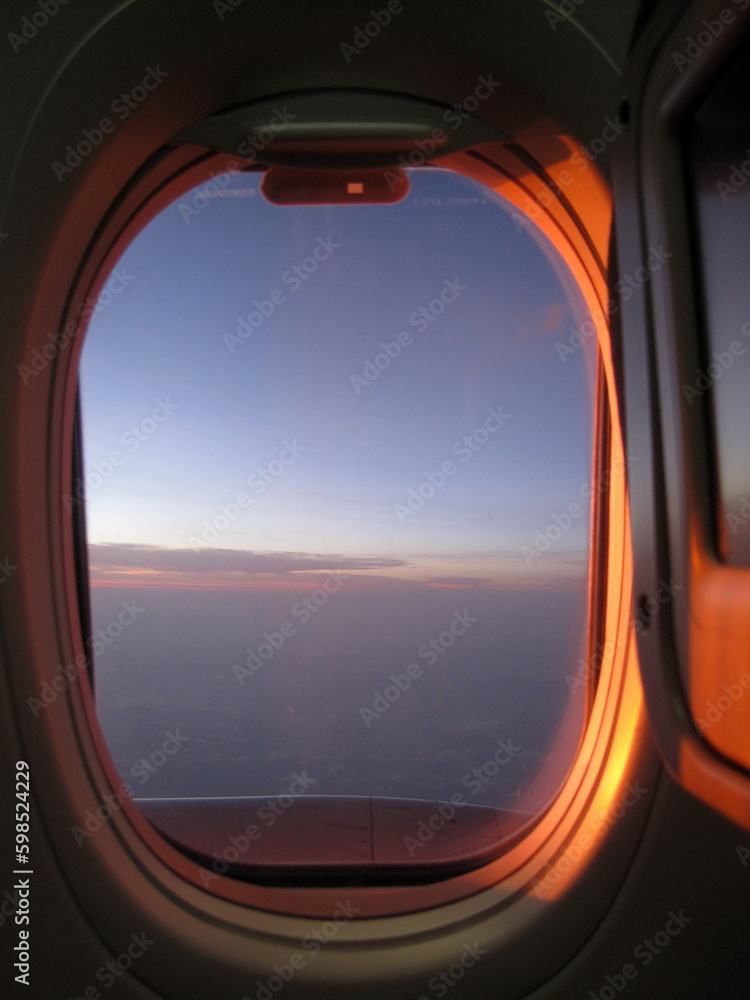 View from the airplane window to the sea and blue sky at sunset