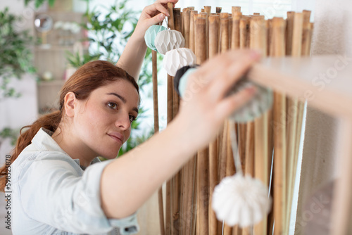 Obraz na plátně woman putting up a paper garland to decorate the home