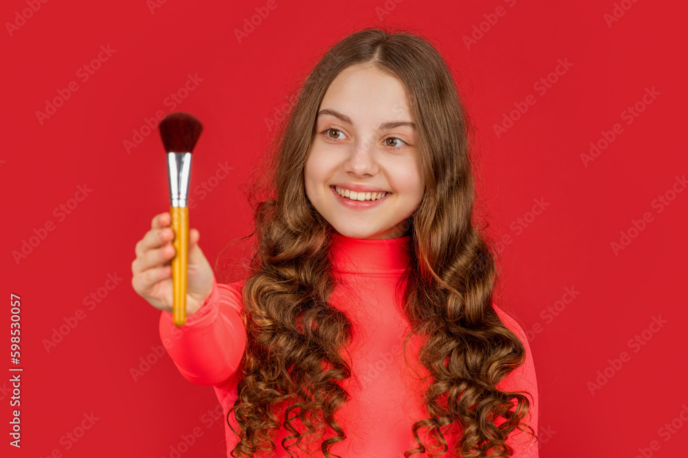smiling kid with curly hair hold powder brush for makeup. selective focus smiling kid with curly hair hold powder brush for makeup. selective focus