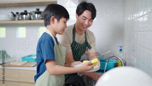 Canvastavla Asian boy helping father washing dish in kitchen at home on holiday