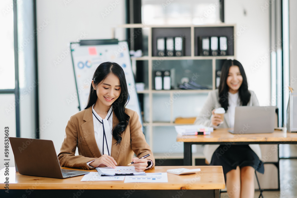 Young attractive Asian female office worker business suits smiling at camera in modern office . Young attractive Asian female office worker business suits smiling at camera in modern office .