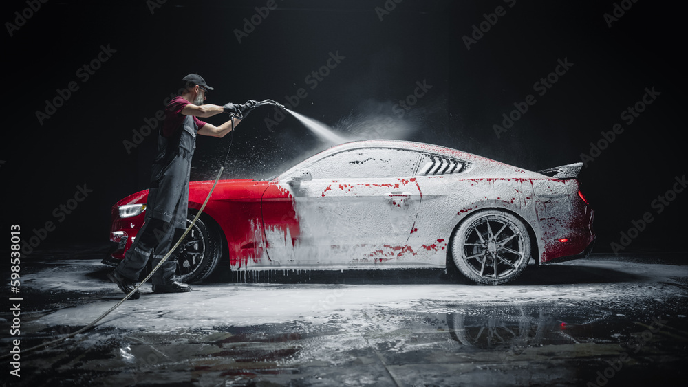 Car Wash Expert Using Water Pressure Washer to Clean a Red Modern