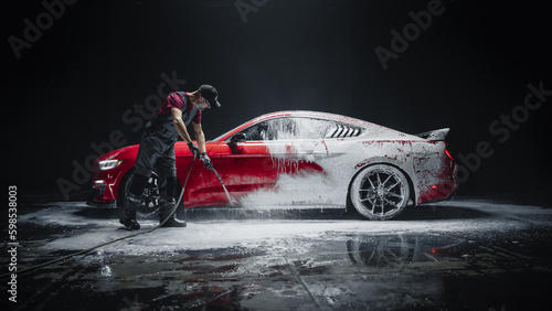 Foto Car Wash Specialist Using Pressure Washer to Rinse a Red Modern Sportscar