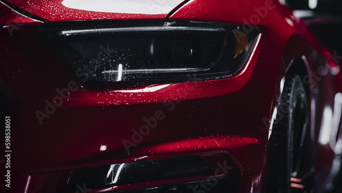 Close Up of a Modern Red Performance Car in a Dark Studio Environment. Creative Led Headlights Footage of a Performance Sportscar Dripping in Water After a Detailed Car Wash © Gorodenkoff