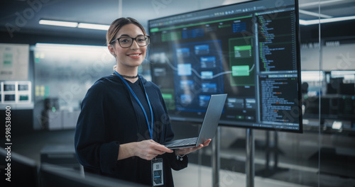 Portrait of a Beautiful Diverse Female Wearing Glasses, Using Laptop Computer, Looking at Camera and Smiling. Information Technology Specialist, Software Engineer or Developer