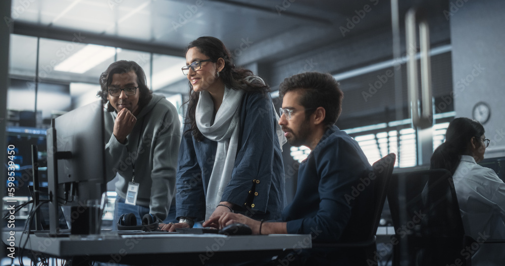 Group of Three Young Indian Software Engineers Use Computer to Discuss a Technological Project in Modern Industrial Office. Group of Male and Female Scientists Work in Research and Development Center Group of Three Young Indian Software Engineers Use Computer to Discuss a Technological Project in Modern Industrial Office. Group of Male and Female Scientists Work in Research and Development Center