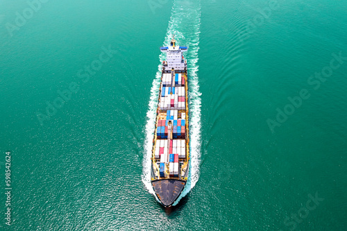 Aerial top view of cargo maritime ship with contrail in the ocean ship carrying container and running for export concept. © Teppakorn