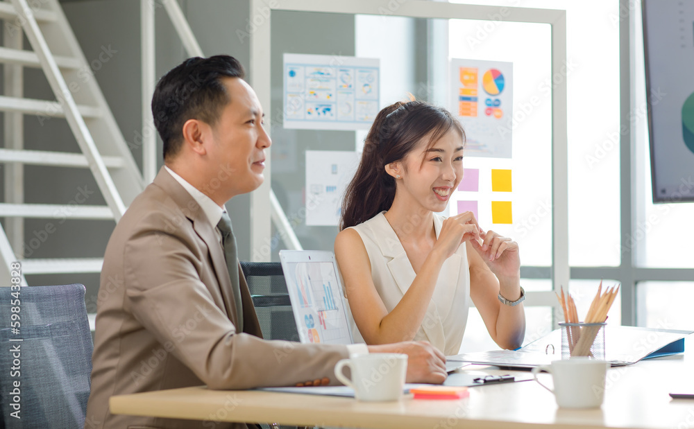 Asian professional successful male businessman manager mentor in formal business suit standing helping teaching supporting female businesswoman colleague sitting working with laptop notebook computer Asian professional successful male businessman manager mentor in formal business suit standing helping teaching supporting female businesswoman colleague sitting working with laptop notebook computer