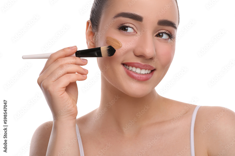 Woman applying foundation on face with brush against white background Woman applying foundation on face with brush against white background