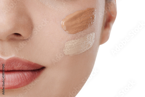 Woman with swatches of foundation on face against white background, closeup