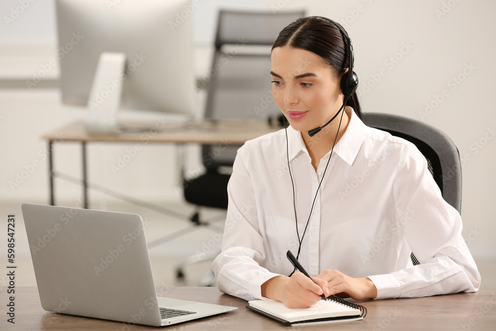 Hotline operator with headset working on laptop in office