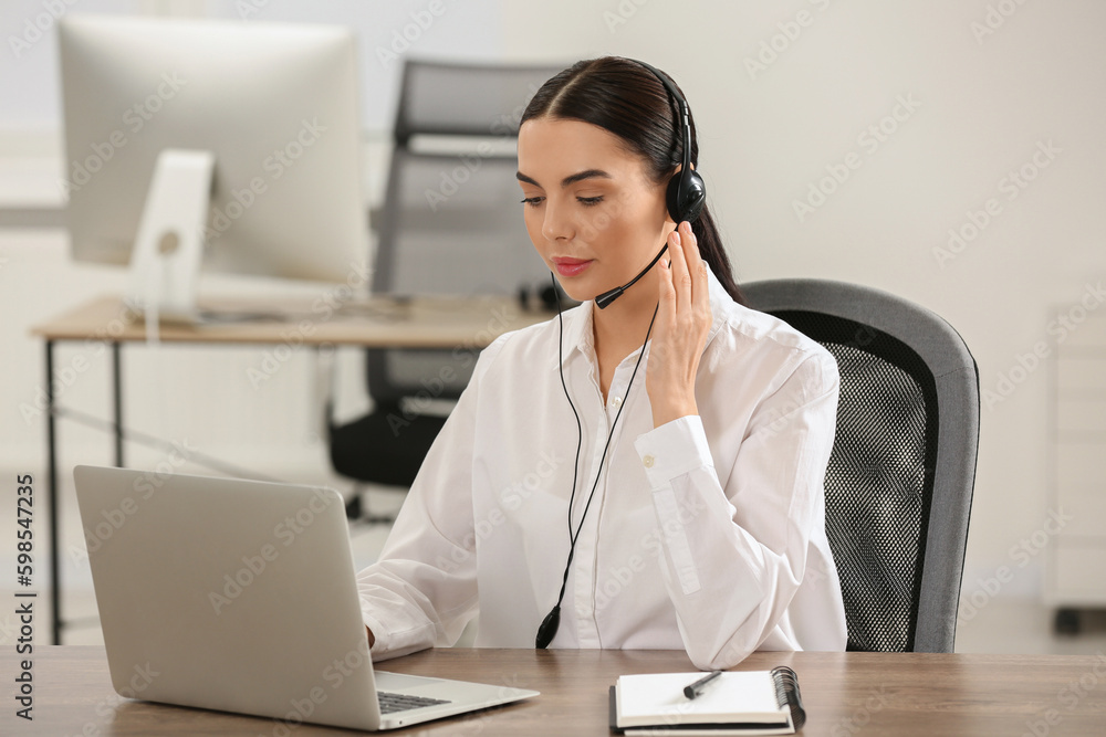 Hotline operator with headset working on laptop in office Hotline operator with headset working on laptop in office