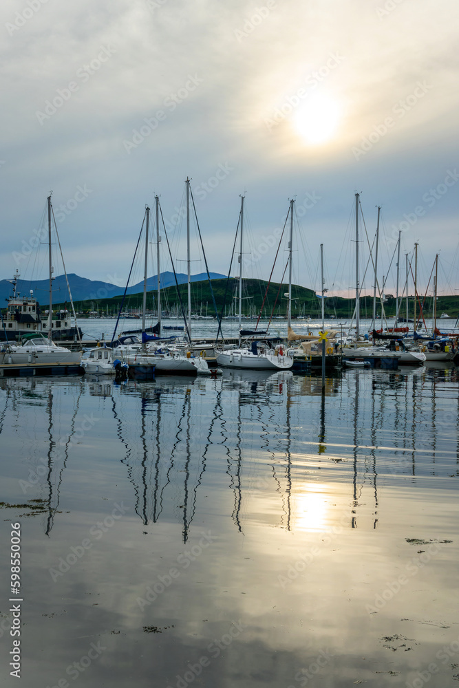 Boats reflection in the harbor of Oban at sunset, in Argyll, Scotland, UK