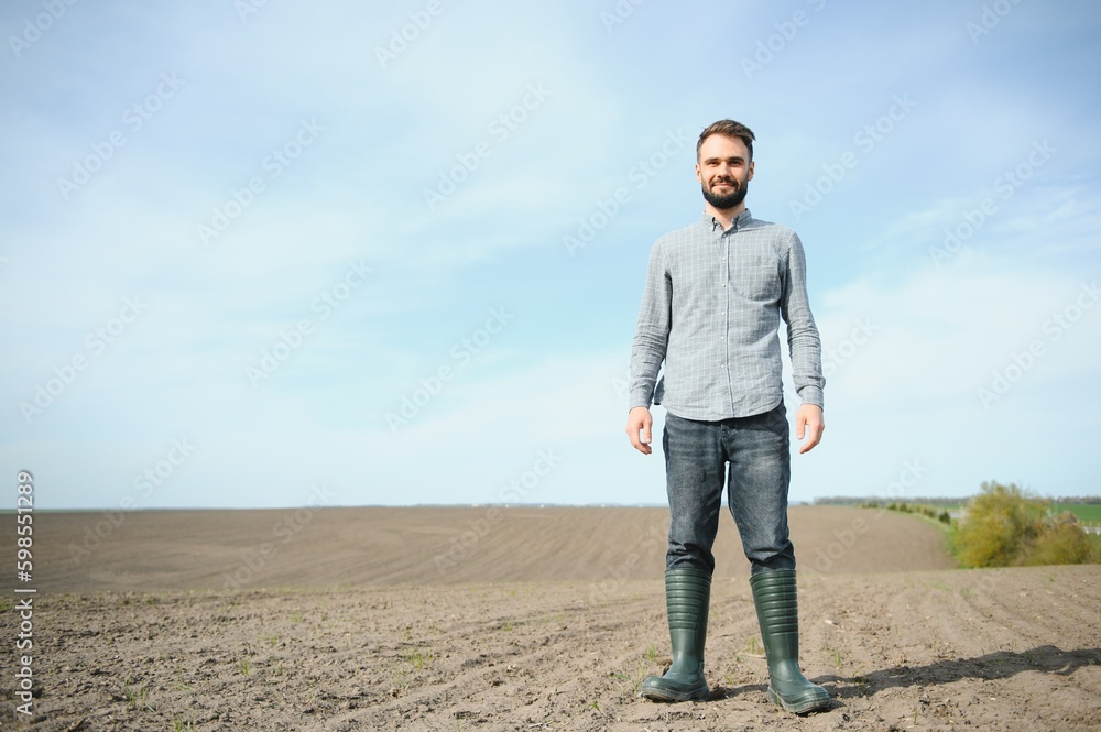A farmer in boots works in a field sown in spring. An agronomist walks the earth, assessing a plowed field in autumn. Agriculture.