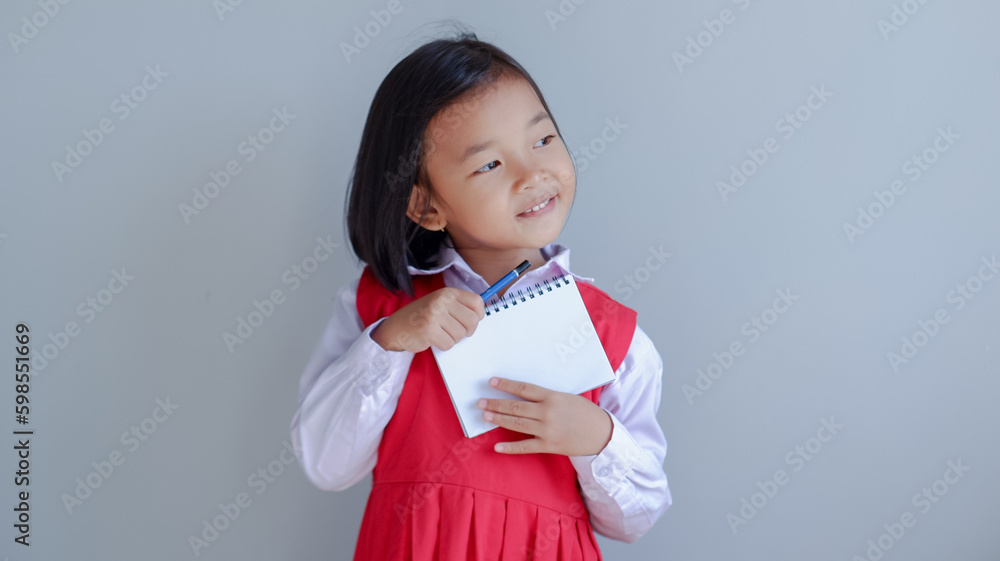 young asian girl wearing school uniform and holding small note book young asian girl wearing school uniform and holding small note book