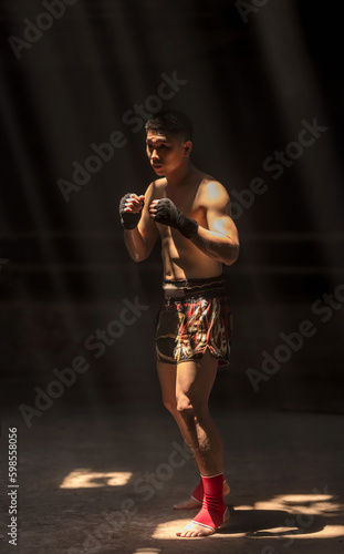 Confident Sport Thai Boxer man standing and guarding up during Muay Thai boxing training