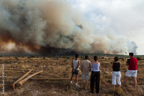 Vecinos observan el humo de un gran incendio forestal cercano a su pueblo. photo