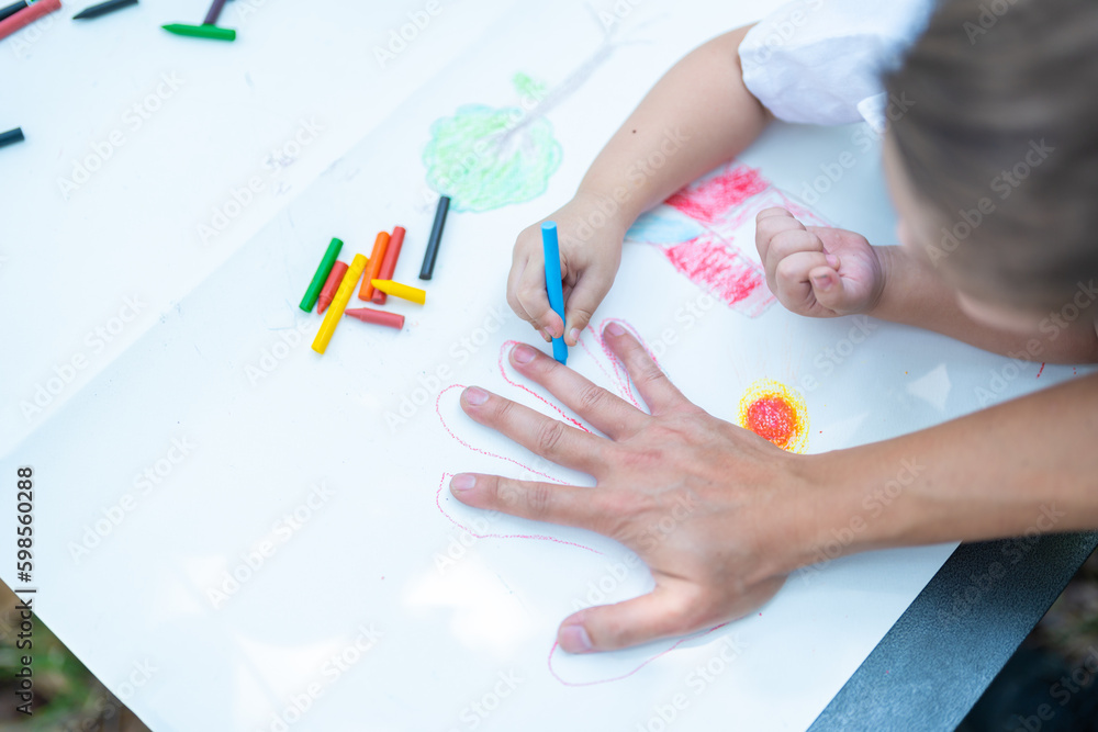 Family activity drawing son using crayons to draw father's hand Family activity drawing son using crayons to draw father's hand