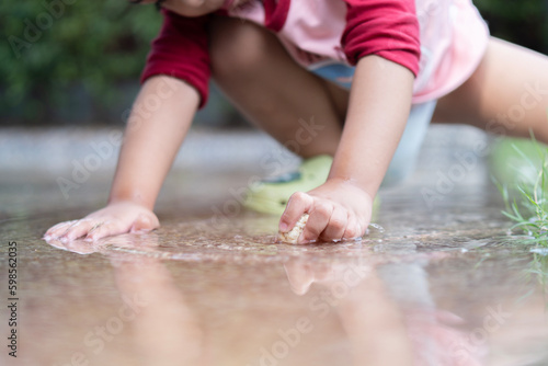 A young boy sit on a concrete floor filled with water. Warm summer or spring day.