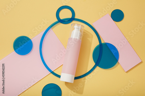 An unbranded pink pump bottle arranged with geometric shape acrylic sheets in blue and pink colors. Blank label for branding mock-up concept