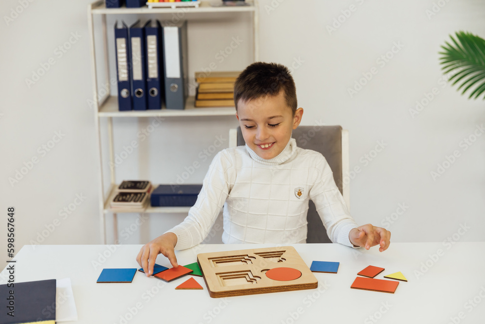 the boy sits at the table with an educational game in the office the boy sits at the table with an educational game in the office
