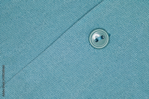 Button buttoned on a green shirt close-up, uniform texture background