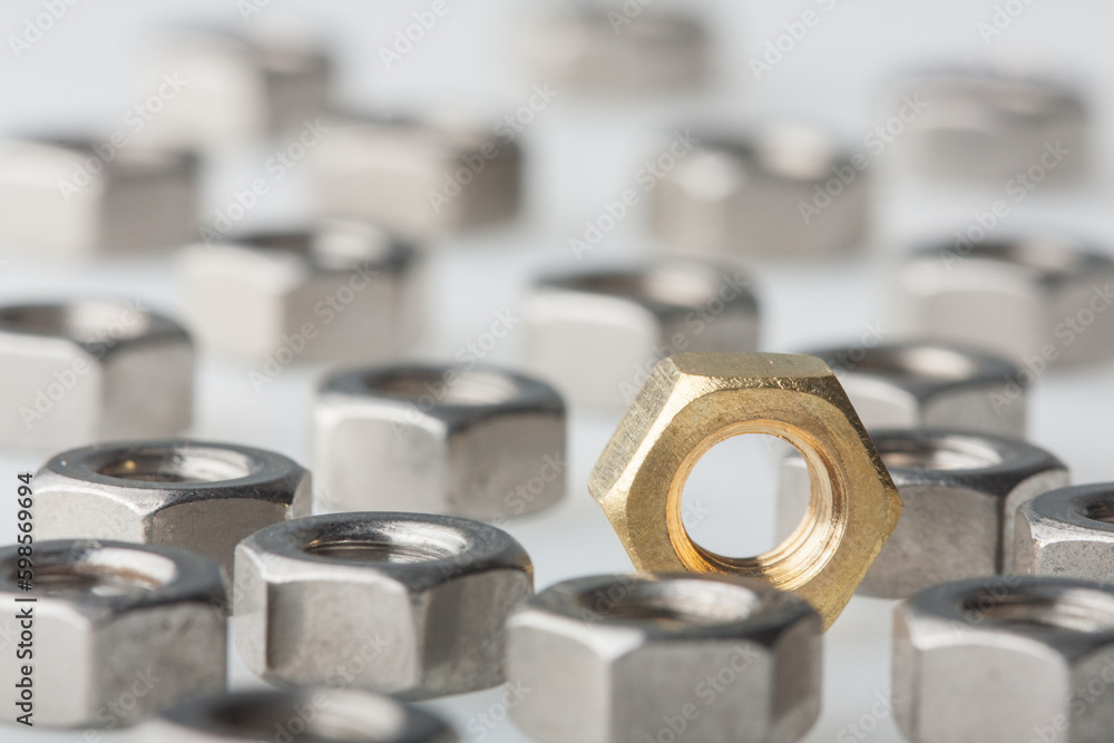 Metallic hex nuts layed out on a table, industrial background. All steel and one brass nut. Selective DOF Metallic hex nuts layed out on a table, industrial background. All steel and one brass nut. Selective DOF