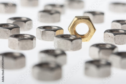 Metallic hex nuts layed out on a table, industrial background. All steel and one brass nut. Selective DOF