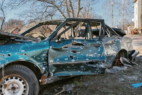 A civilian car is damaged by fragments of artillery shells. Side view