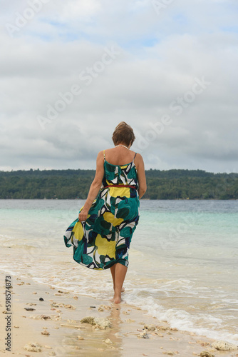 Unhappy attractive woman feeling sad at the beach. Senior woman wear the green long dress. The island on the background.