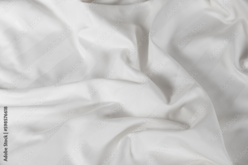 Satin crumpled fabric of white color, top view. Natural bed linen, sheets, abstract background of luxury fabric, wavy folds