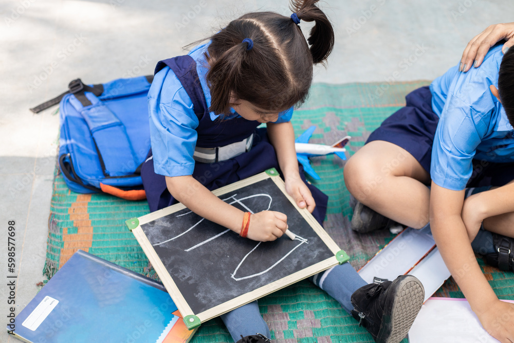 cute-little-indian-girl-student-wearing-school-uniform-writing-on-slate