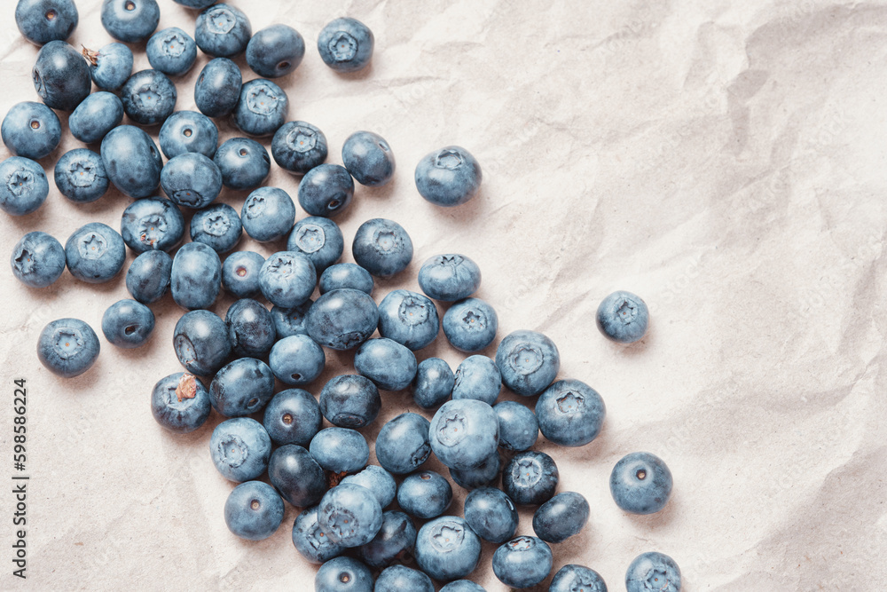 Fresh blueberries scattered on beige craft paper.